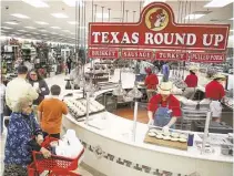  ??  ?? Shoppers look over the barbecue station at the Buc-ee’s in Baytown. The chain is based in Lake Jackson.