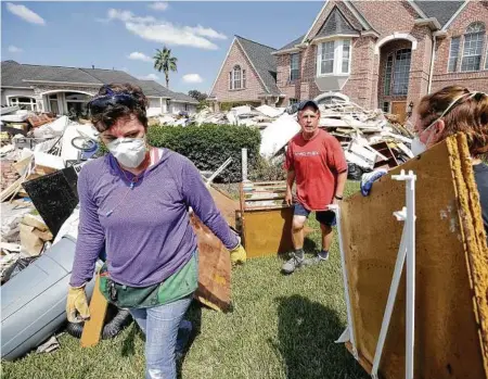  ?? Melissa Phillip / Houston Chronicle ?? Tom Mayne (centro), miembro de la iglesia Bautista de Champion Forest Baptist, participa de las tareas de recuperaci­ón en Stuebner Airline Rd. luego del paso de la tormenta tropical Harvey por el área de Houston.