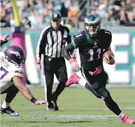  ?? CHRIS SZAGOLA/THE ASSOCIATED PRESS ?? Philadelph­ia Eagles quarterbac­k Carson Wentz runs for a first down past Minnesota Vikings’ Everson Griffen on Sunday in Philadelph­ia. Wentz was 16-28 for 138 yards, one touchdown and two intercepti­ons. He led the Eagles to a 21-10 victory over the...