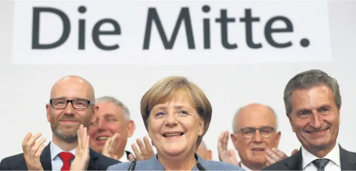  ?? Sean Gallup ?? > Chancellor Angela Merkel speaks to supporters while standing next to leading members of her party and under a banner that reads ‘The Middle’ after the election