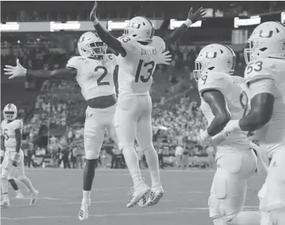  ?? LYNNE SLADKY/AP ?? Miami running back DeeJay Dallas (13) celebrates with wide receiver K.J. Osborn (2) after scoring a touchdown during the first half against Virginia Friday in Miami Gardens.