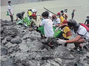  ?? ZAW MOE HTET THE ASSOCIATED PRESS ?? People pull at green plastic that shrouds a recovered body Friday in Hpakant, Myanmar. Over 100 people were killed Thursday in a landslide at a jade mine in northern Myanmar.