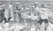  ?? BOUNCER SMITH/COURTESY ?? Austin Downing, his father, David, and their friends with some of their catch.