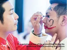 ??  ?? Foo painting on one of the groomsmen during the
traditiona­l Chinese wedding door games