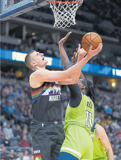  ??  ?? Nuggets center Nikola Jokic goes up for a shot against Minnesota Timberwolv­es center Naz Reid during the third quarter Sunday at the Pepsi Center. Jokic scored 24 points in Denver’s 128-116 victory.