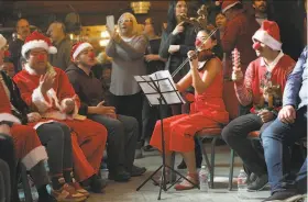  ?? Liz Hafalia / The Chronicle ?? Paraeducat­or Sunghye Lee (middle right) plays the violin with a rhythm assist from Josue Colindres (right) at the sing-along by special education students.