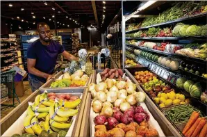  ?? STEVE SCHAEFER / FOR THE AJC ?? Even as some places have closed amid the pandemic, others are opening and hiring, such as the new Nuts ’n Berries Decatur, where Karon Ford works on organizing the produce Tuesday before its soft opening in the former Rainbow Natural Foods location.