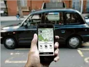  ?? DANIEL LEAL-OLIVAS/GETTY-AFP ?? A smartphone displays the Uber app as a London black cab passes. London won’t renew Uber’s license to operate.