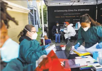  ?? Gabrielle Lurie / The Chronicle ?? Nurse Anna Briggs (background right) chats with a patient with before administer­ing the Johnson & Johnson vaccine at the Center for Empowering Refugees in Oakland.