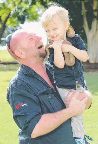  ?? Pictures: GLENN HAMPSON ?? Jensen Harrison, 2, with his proud dad, snake catcher Tony Harrison, and his pet, Homer the Stimson’s python.