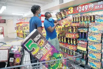  ?? AMY BETH BENNETT/SOUTH FLORIDA SUN SENTINEL ?? Russell Jackson loads earth shakers into his cart with Delisceo Jackson, both of Westpark, at TNT Fireworks in Dania Beach.