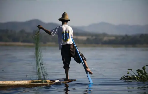  ?? AFP/GETTY IMAGES ?? On Inle Lake, centuries-old traditions linger. The local Intha tribespeop­le still propel their skiffs with leg rowing, by wrapping one leg around the oar to drive the blade through the water.