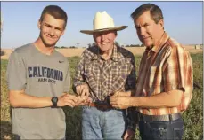  ??  ?? Taken one month before his 100th birthday, Bill DuBois (center) shows his son and grandson how to judge moisture levels in alfalfa. COURTESY PHOTO