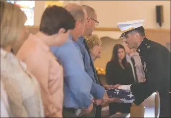  ?? NEWS-SENTINEL PHOTOGRAPH­S BY BEA AHBECK ?? Combat Logistics Battalion Capt. Jonathan Tenbrock presents the American flag to Carolyn Johnson, wife of late council member and former mayor Bob Johnson, during a memorial service for him at St. Anne’s Catholic Church in Lodi on Thursday.