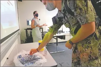  ?? (AP/Julio Cortez) ?? A midshipman reaches for sanitizing wipes Aug. 24 while arriving to a leadership class taught by professor Celeste Luning (left) at the Naval Academy in Annapolis, Md.