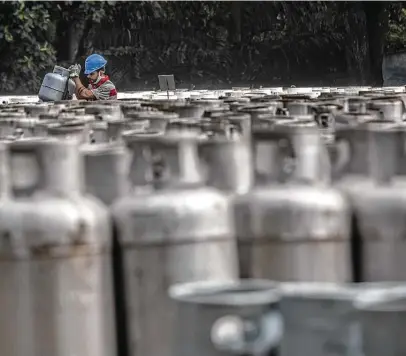  ?? Bloomberg file photo ?? A worker organizes canisters of cooking gas last month near a Petrobras refinery in Duque de Caxias, Brazil. With the global economy rebounding from the COVID-19 pandemic, demand for energy in all forms is strong.