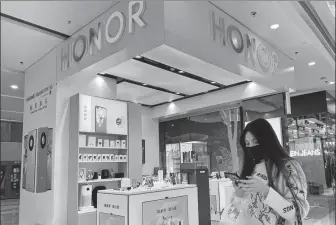  ?? CHEN HAO / FOR CHINA DAILY ?? A shopper looks at her mobile phone at an Honor store in Putian, Fujian province.