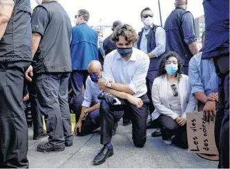  ?? REUTERS ?? Prime Minister Justin Trudeau wears a mask as he takes a knee during a rally against the death in Minneapoli­s police custody of George Floyd, on Parliament Hill, in Ottawa on June 5.