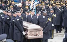  ??  ?? Pallbearer­s prepare to place Cmdr. Paul Bauer’s casket into a hearse after the funeral.