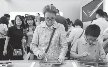  ?? WANG ZHENGWEI / FOR CHINA DAILY ?? Consumers try out iPads at a flagship Apple store in Chengdu, capital of Sichuan province.