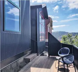  ??  ?? The homes’ dark Colorsteel cladding is punctuated with red and green window frames.