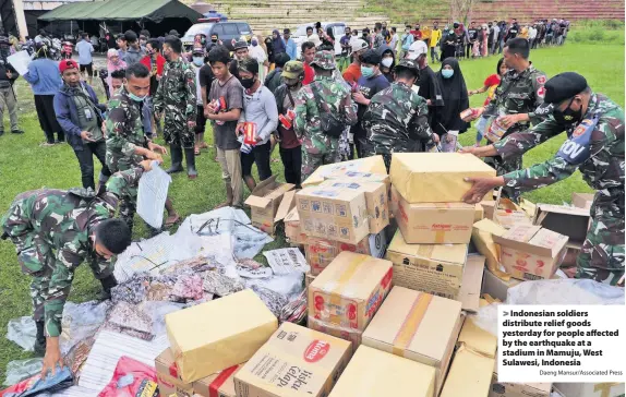  ?? Daeng Mansur/Associated Press ?? Indonesian soldiers distribute relief goods yesterday for people affected by the earthquake at a stadium in Mamuju, West Sulawesi, Indonesia