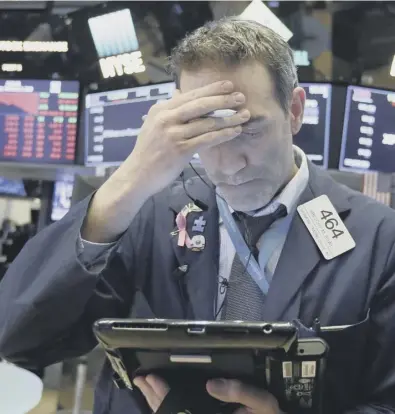  ??  ?? 0 A trader works on the floor of the New York Stock Exchange as shares slump in value