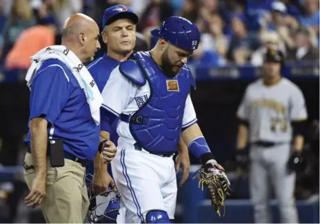  ?? NATHAN DENETTE/THE CANADIAN PRESS ?? Trainer George Poulis and manager John Gibbons respond after Jays catcher Russell Martin signals he’s done for the night with an oblique injury.