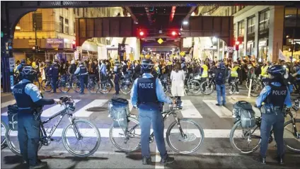  ?? Chicago Sun-Times file photo via AP ?? Chicago police officers keep watch as protesters march through the Loop in Chicago on Nov. 4. New research suggests hiring more nonwhite and female officers could help improve police treatment of people of color, according to a new study published Thursday in the journal Science.