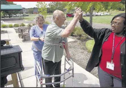  ?? BRANDON DILL / SPECIAL TO THE COMMERCIAL APPEAL ?? Memphis Jewish Home & Rehab patient Jim DiSalvo, 78, gets a high-five from therapy director Yolanda Holley-Whitmore while physical therapy assistant Debra Forbes assists him in the therapy garden at the facility’s grounds in Cordova. The facility is...