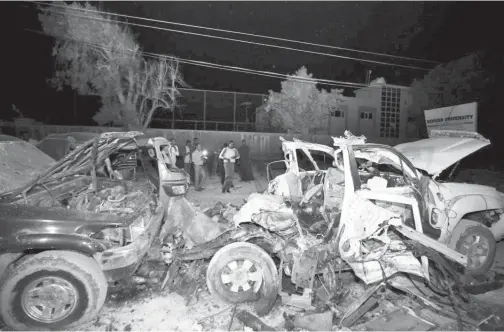  ?? — Gambar Reuters ?? PEGAWAI polis dan wartawan berhimpun dekat rangka kenderaan yang musnah selepas sebuah bom kereta meletup di pekarangan restoran Banadir berhampira­n Pantai Lido di Mogadishu, Somalia kelmarin.