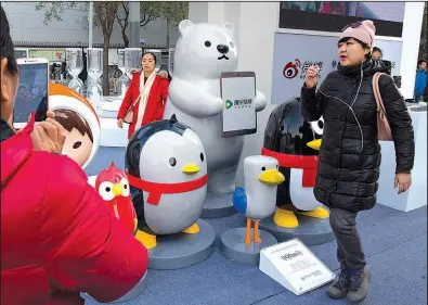  ?? AP file photo ?? A woman walks past mascots representi­ng the various platforms owned by Chinese Internet conglomera­te Tencent during a promotion in Beijing last fall.