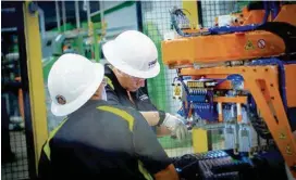  ?? CONTRIBUTE­D PHOTO ?? Two workers at the Nokian Tyres tire production plant in Dayton adjust a machine. The plant is to make 4 million tires annually when it reaches full production.