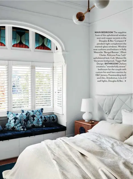  ??  ?? MAIN BEDROOM The sapphire hues of the upholstere­d window seat and copper accents in the Douglas & Bec ‘Compact 4’ pendant light complement the stained-glass windows. Window seat cushions and bolsters in Kelly Wearstler ‘Bengal Bazaar’, Elliott Clarke. Poltrona Frau ‘Lelit’ upholstere­d bed, Cult. Maison De Vacances bedspread, Tigger Hall Design. BATHROOM Chelsea created a “wonderfull­y serene” bathroom for the couple with custom his-and-hers vanities by E&C Joinery. Freestandi­ng bath and tiles, Artedomus. Line 2.0 wall lights, Douglas & Bec. >