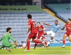  ??  ?? Manchester City forward Raheem Sterling (in blue) slots the ball home