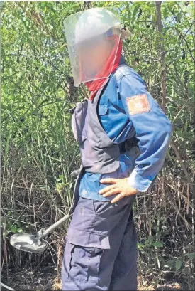  ??  ?? A Halo Trust worker in protective gear clears mines in Cambodia