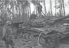  ?? RODRIGO ABD/AP ?? A Ukrainian soldier stands on a destroyed Russian tank on the outskirts of Kyiv, Ukraine, on Thursday.