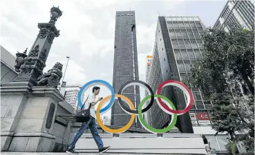  ?? Picture: Tomohiro Ohsumi/Getty Images ?? A man walks past the Olympic rings in the Nihombashi district of Tokyo, Japan, earlier this year.