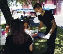  ??  ?? Bao Nguyen serves customers outside at Pho Ha Noi restaurant in Cupertino on July 6. Santa Clara County restaurant­s are having to deal with conflictin­g state and local orders pertaining to outdoor dining.