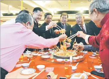  ??  ?? Ting (centre) joins guests in tossing the ‘Yee Sang’ at the dinner.