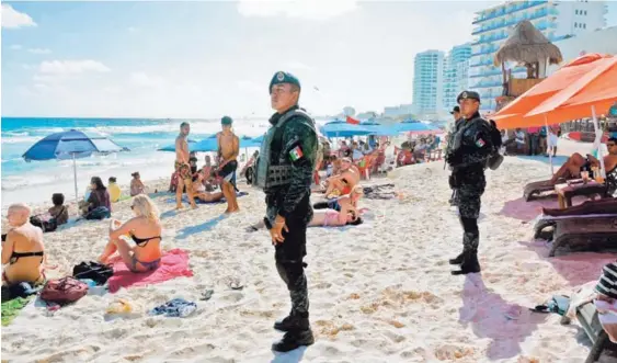  ?? AFP Y AP ?? Miembros de la Policía Federal vigilaban ayer una playa en Cancún, luego de un ataque contra el edificio de la Fiscalía de Quintana Roo, ubicado en esa ciudad. Después de ese suceso, agentes desalojaro­n un centro comercial por una alerta de violencia...