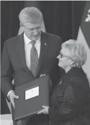  ?? GRAHAM HUGHES/THE CANADIAN PRESS ?? Prime Minister Stephen Harper presents Lac Mégantic Mayor Colette Roy-Laroche with a book of condolence­s after a news conference in Lac Megantic, Que. on Thursday.