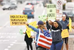  ?? JOHN GASTALDO FOR THE U-T ?? Benji Gelbart (with flag), whose grandmothe­r is a Holocaust survivor, joins a group Oct. 13 in Encinitas protesting use of an Adolf Hitler photo at a school.
