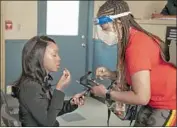  ??  ?? MAKEUP ARTIST Syretta Bell, right, wears protective gear to work with actress Ebony Obsidian.