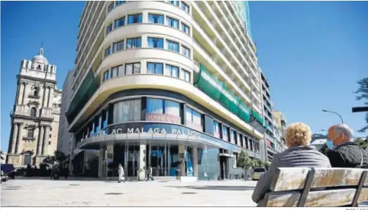  ?? MARILÚ BÁEZ ?? Dos personas mayores sentadas en un banco frente a un hotel en el centro de Málaga.