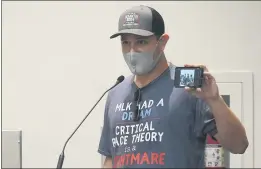  ?? MARTA LAVANDIER — THE ASSOCIATED PRESS ?? Elon Gerberg holds up a picture of his two young children singing and dancing at a private day care during the Broward School Board’s emergency meeting Wednesday in Fort Lauderdale, Fla., where the members listened to parents’ concerns on mask use.