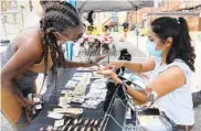  ??  ?? Gracie Williams of Baltimore, left, looks at jewelry made by Marina Delgado of Essex, right, at the Latin America Culture Market, which is held occasional­ly on Saturdays in Highlandto­wn across from the Creative Alliance at the Patterson.