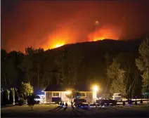  ??  ?? A wildfire burns on a mountain behind a home in Cache Creek, B.C., in the early morning hours of Saturday.