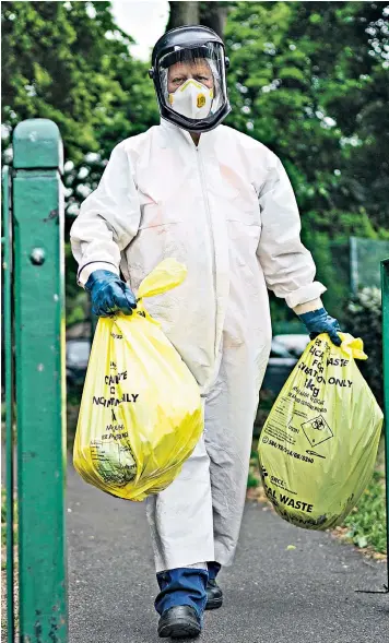  ??  ?? A city council worker carries rubbish from a coronaviru­s testing centre yesterday, in Leicester, which is experienci­ng a surge in cases