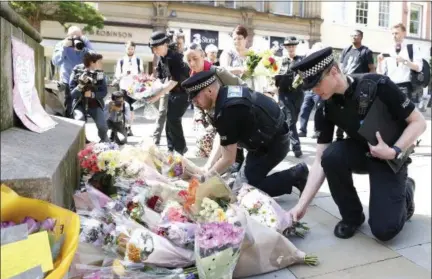  ?? PHOTOS BY THE ASSOCIATED PRESS ?? Police officers add to the flowers for the victims of Monday night pop concert explosion, in St Ann’s Square, Manchester, Tuesday May 23, 2017.